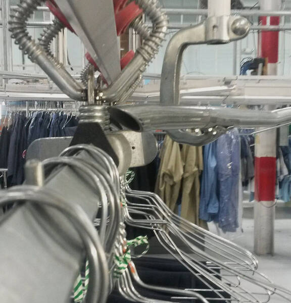 A line of uniforms on hangers going through a sorting machine